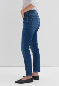 Donkerblauwe jeans met een slim fit, gemaakt van denim. Bevat vijf zakken, riemlussen en subtiele stiksels langs de zijkanten.