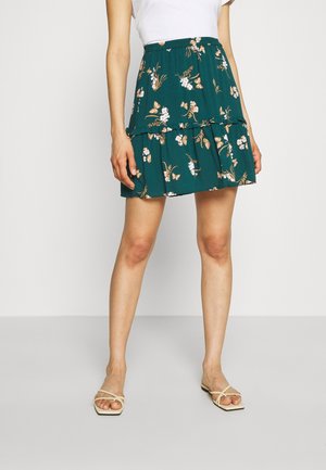 Rok met bloemenprint in donker teal met geplooide lagen, gemaakt van lichtgewicht stof. Bevat witte, roze en oranje bloemen- en vlinderpatronen.