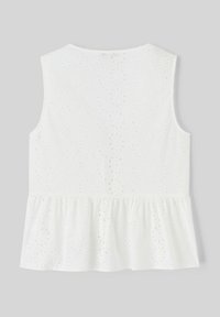 Haut peplum blanc avec découpes en œillets, sans manches et finition en tissu texturé. La vue arrière montre un détail d'ourlet volé.