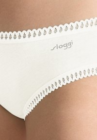 Hvidt bomuldsbikiniunderdel med bølget blondestrimle og et diskret logo, glat tekstur og tætsiddende pasform.