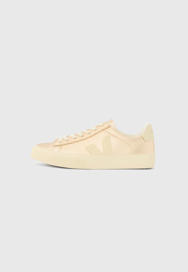Beige lavsko-sneaker med lisser, gummisåle og en "V"-logo på siden, vist i høyre sideprofil på en ensfarget bakgrunn.