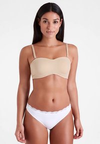 Beige bra with a smooth, seamless design and adjustable straps, paired with white lace-trimmed panties. Both have a simple, minimalist style.