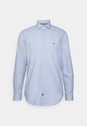 Camicia azzurro chiaro a maniche lunghe con bottoni, collo appuntito e piccolo logo sul petto sinistro, mostrata su sfondo semplice.