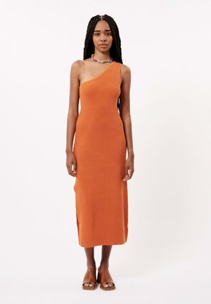 Robe midi à une épaule, en tissu tricoté côtelé orange. Comprend une fente sur le côté, une silhouette ajustée, et est associée à des sandales brunes à bout ouvert.