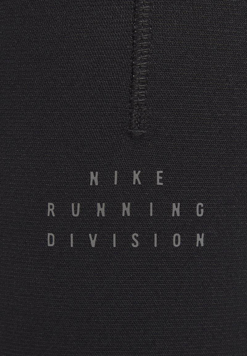 Tissu athlétique noir avec des coutures visibles. Le texte centré indique "NIKE RUNNING DIVISION" en une police claire et audacieuse. Texture lisse.