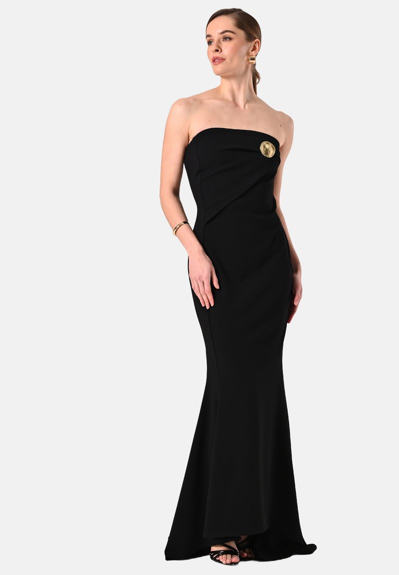 Schwarzes trägerloses Abendkleid mit figurbetontem Schnitt, drapiertem Design und goldfarbener Akzentnadel. Bodenlang mit einem ausgestellten Saum, hergestellt aus glattem Stoff.