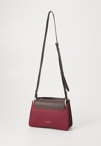 Sac bandoulière en cuir avec un corps texturé bordeaux et un rabat lisse marron foncé. Bandoulière réglable et accents en métal doré.
