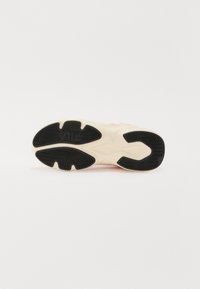 Baskets FILA avec une semelle intermédiaire épaisse crème, une semelle en caoutchouc noir et des accents roses. Présentent une surface texturée et un motif de semelle unique.