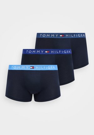 Három pár sötétkék férfi boxeralsó elasztikus derékpánttal, különböző kék árnyalatokban, mindegyiken "Tommy Hilfiger" márkajelzés és logó.