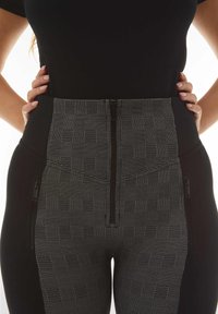 Body nero con design alto in vita e texture. Presenta un pannello decorato, zip laterali e un tessuto liscio.