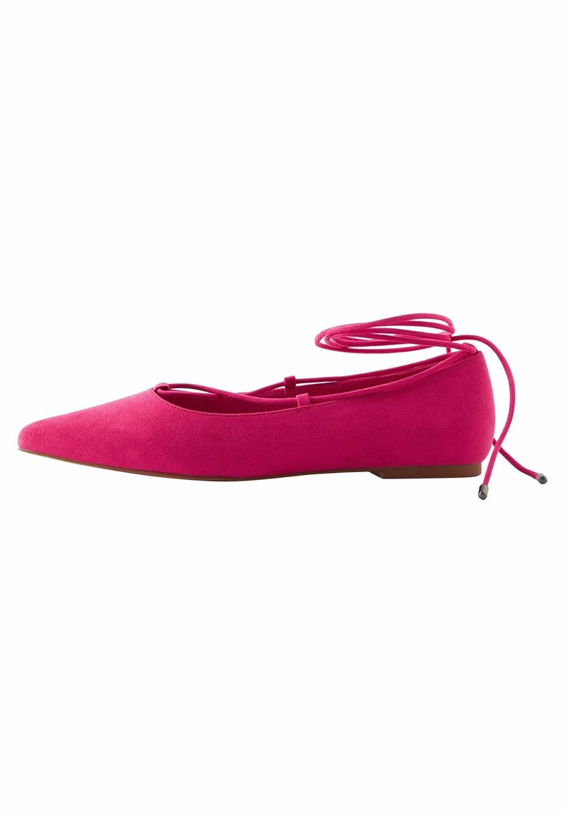 Chaussure plate rose vif à bout pointu avec lacets enveloppants autour de la cheville et semelle basse marron, présentée sur un fond blanc.