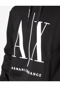 Felpa con cappuccio nera in cotone, caratterizzata da grandi scritte bianche "AX" e "ARMANI EXCHANGE" stampate sulla parte anteriore. Coulisse regolabile.