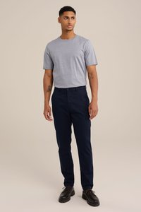 Pelēks īsās piedurknes T-krekls ar apaļu kaklu, apvienots ar tumši ziliem biksēm un melnām kurpēm. Apģērbs ir vienkārša dizaina.