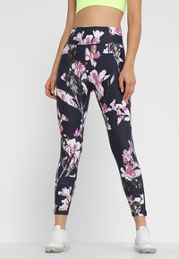 Námořnické legíny s květinovým vzorem, které obsahují velké růžové a bílé květy. Vyrobené z elastického materiálu s vysokým pasem a délce po kotníky.