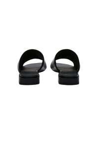 Black slide sandals featuring a smooth leather upper, minimalist design, open back, and flat sole with subtle branding on the insole.