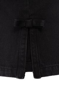 Il tessuto di denim nero presenta un dettaglio a fiocco in vita, con una finitura pulita e una texture sottile. Il design include due anelli di tessuto.