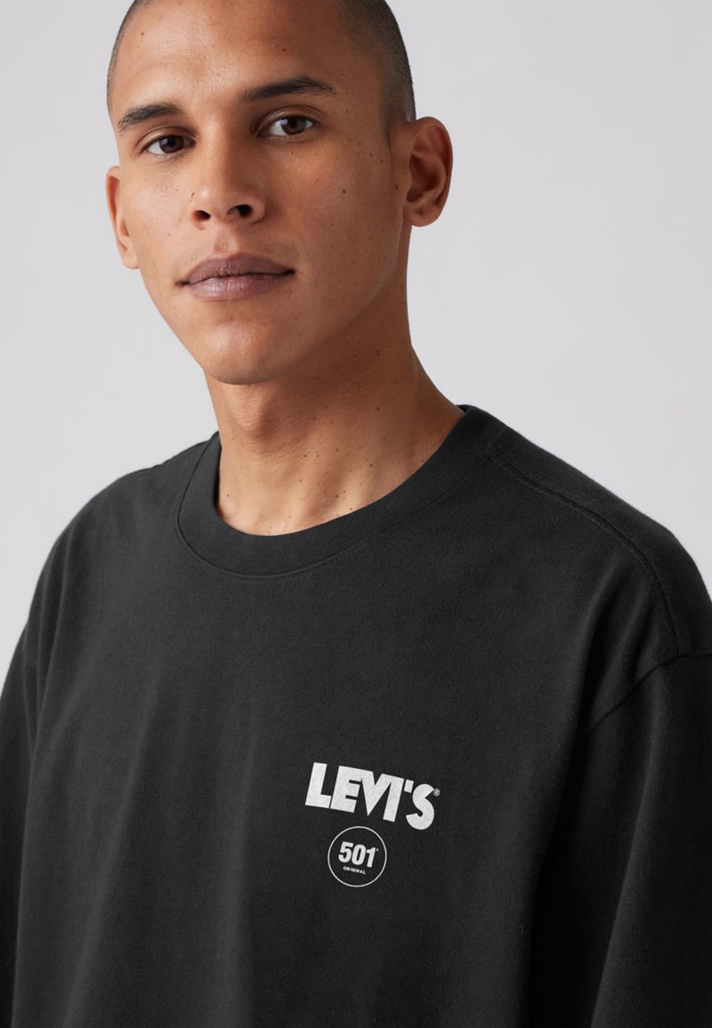 Zwart katoenen T-shirt met ronde hals, korte mouwen en een wit grafisch logo op de borst, met duidelijk zichtbaar detail "Levi's 501".
