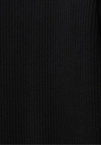 Texture de tissu noir côtelé avec des lignes verticales créant un motif subtil et de légères variations de nuances.