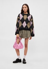 Πλεκτό πουλόβερ με ρόμβους σε μαύρο, ροζ και ελιά χρώμα; μίνι καρό φούστα; ροζ τσαντάκι; μαύρα παπούτσια με κορδόνια; λευκές κάλτσες.