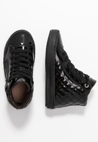 Sorte patentlæder højtop sneakers med quiltet sidestruktur, sorte snørebånd, gummisål og en brun stofforing.