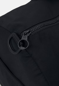 Zaino in nylon nero con finitura testurizzata, caratterizzato da una cerniera prominente e un tirante circolare per un accesso facile.