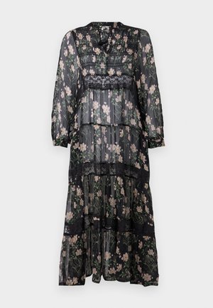 Musta kukallinen mekko, jossa on pitkät läpinäkyvät hihat, pitsikoristelu ja kerroksellinen helma. Mukana sopivat mustat polven yli ulottuvat saappaat.