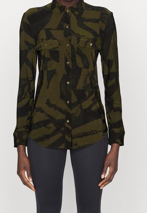 Closely fitted long-sleeve button-up shirt with dark green and black abstract camouflage pattern and two chest pockets with gold buttons.