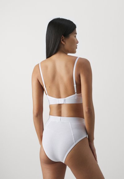 Hvit ribbet bralette med justerbare stropper og krokfeste, sammen med høytalergenererte hvite truser. Glatt tekstur, minimalistisk design.