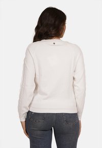 Pullover bianco con maniche lunghe, polsini e orlo a coste, caratterizzato da un piccolo logo sul colletto posteriore e pannelli laterali testurizzati.