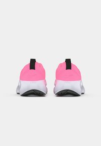 Nike-sko med en lys rosa overdel med teksturert finish, svart trekkflik og en hvit mellomsåle med svart gummisåle.