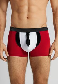 Calzoncillos bóxer rojos y negros con un panel frontal blanco y negro, que presenta un diseño decorativo de corbata negra. Hechos de tela elástica.