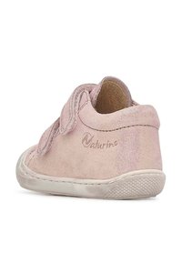 Světlé růžové semišové dětské botičky s páskem na suchý zip, zaoblenou špičkou, texturovanou podešví a nenápadným logem na boku.