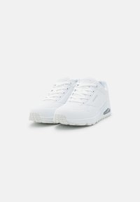 Weiße Sportschuhe mit Obermaterial aus Netz und Synthetik, Schnürverschluss, gepolsterter Zunge und weißer Laufsohle mit sichtbarem Luftpolster.