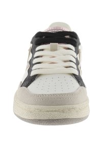 Zapatilla blanca y negra con puntera de ante beige, diseño perforado, cordones blancos y detalles dorados en los lados. Suela de caucho texturizada.