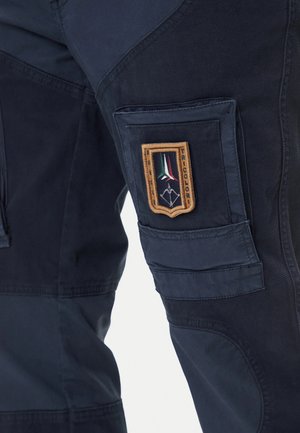 Pantaloni da lavoro blu scuro realizzati in tessuto resistente, con una tasca applicata e un distintivo ricamato con accenti tricolori.