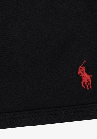 Tela de algodón negra con un pequeño logo de polo bordado en rojo, con una textura suave y un diseño simple y limpio.