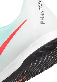Hele helesinine spordijalats punase triibuga, tekstuurne must väliskumm ja küljes must 'PHANTOM' bränding. Voogav disain.