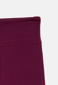 Burgundijas legingi ar gludu tekstūru, platām elastīgām jostām un plakanajām šuvēm komfortam. Audums izskatās stiepjams un mīksts.
