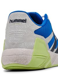 Blaue und graue Sportschuhe mit strukturiertem weißen Fersenbereich, grünen Akzenten und einem Obermaterial aus Mesh. Die Ferse weist ein kartengleiches Muster auf.