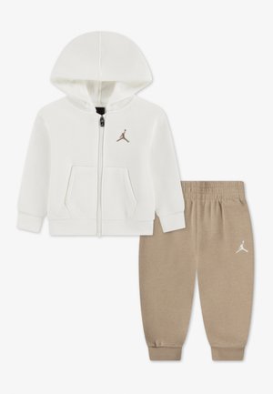 Veste blanche zippée à capuche avec poches avant et pantalon beige à taille élastiquée, tous deux avec un petit logo Jumpman.
