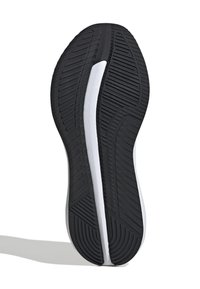 Black rubber shoe sole with distinct tread pattern, featuring a white midsole stripe and rounded edges for flexibility and grip.