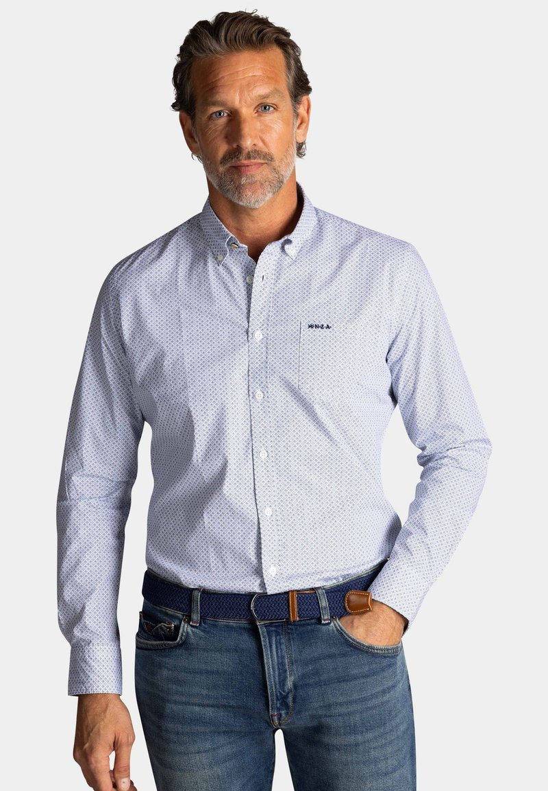 Lichtblauw overhemd met kleine witte patronen, slim fit, lange mouwen en een borstzak, gecombineerd met donkere jeans en een bruine riem.