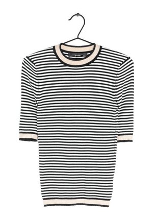 Pull à manches courtes à rayures horizontales noires et blanches avec bordure beige au col, aux manches et à l'ourlet, suspendu sur un cintre noir.