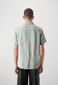 Korte mouwen shirt in lichtblauw, met een gestructureerde stof met verticale strepen en een knoopsluiting kraag. Losse pasvorm, gebogen zoom, casual stijl.