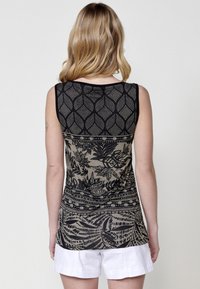 Débardeur sans manches présentant un motif botanique noir et beige. Le design comprend des textures géométriques et des motifs de feuilles intriqués. Matière douce.