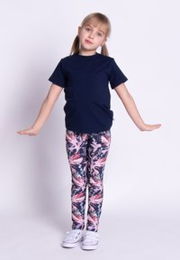 Granatowa koszulka z krótkim rękawem i bezszwowym wzorem, zestawiona z kolorowymi legginsami w kwiaty. Dopełnieniem stroju są białe trampki.