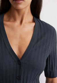 Ciemnoszary prążkowany top z głębokim dekoltem w serek, krótkimi rękawami oraz detalem w postaci guzika z przodu, wykonany z textured dzianiny.