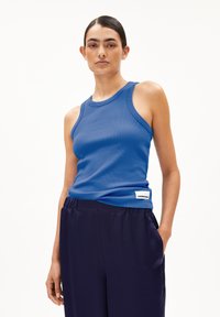 Blue ribbed tank top with a round neckline and shoulder straps, paired with navy satin pants featuring side pockets.
