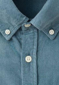 Blå kordflodsskjorta med spetsig krage, knappstängning fram med vita knappar och texturerad ribbad tyg.