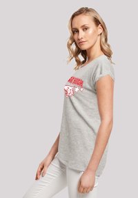 Lys grå t-shirt lavet af bomuld, med korte rullede ærmer og et rødt grafisk design med en ulv og stjerner på forsiden.